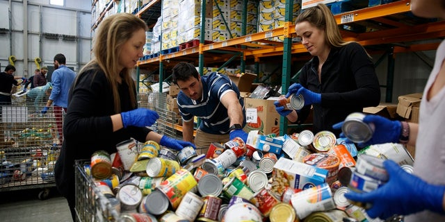 George Washington University School of Medicine students, Katie Coerdt, Paige Dekker, and Caitlin Merely sort canned food as they wear disposable gloves at Capital Area Food Bank in Washington on Thursday. The students are volunteering at the food bank because their medical rounds were cancelled because of the coronavirus outbreak.