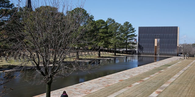 A visitor sits next to the reflecting pool at the Oklahoma City National Memorial and Museum in Oklahoma City, Okla., March 18, 2020. (Associated Press)