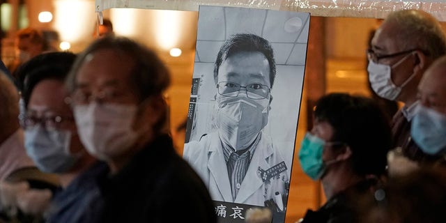 In this Feb. 7, 2020, file photo, people wearing masks attend a vigil for Chinese doctor Li Wenliang, who was reprimanded for warning about the outbreak of the new coronavirus, in Hong Kong. 