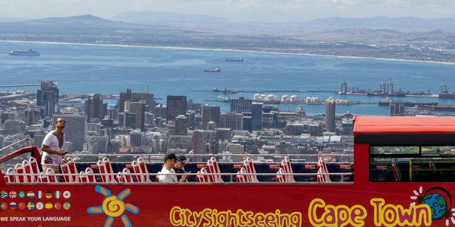 An open-air double decker sightseeing bus, which is virtually empty, stops on the slopes of Table Mountain, overlooking the city of Cape Town, South Africa, Friday March, 20, 2020, as plans are in place to prevent the spread of the coronavirus. For most people the virus causes mild or moderate symptoms, but for others it causes severe illness. (AP Photo)