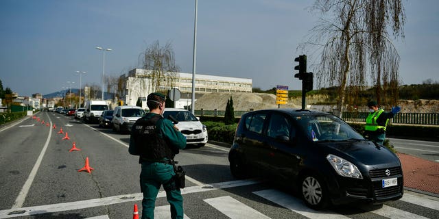 Spanish Civil Guard officers at a checkpoint to stop drivers from trying to leave the city, in Pamplona, northern Spain, Saturday, March 21, 2020. For many people the coronavirus causes mild or moderate symptoms, but for some it causes more severe illness, especially in older adults and people with existing health problems. (AP Photo/Alvaro Barrientos)