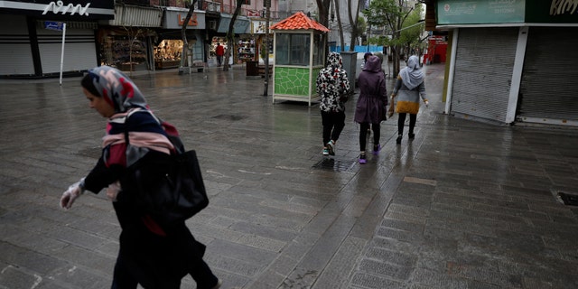 People walk in a mostly empty street in a commercial district in downtown Tehran, Iran, Sunday, March 22, 2020. on Sunday, Iran imposed a two-week closure on major shopping malls and centers across the country to prevent spreading the new coronavirus. Pharmacies, supermarkets, groceries and bakeries will remain open. (AP Photo/Vahid Salemi)