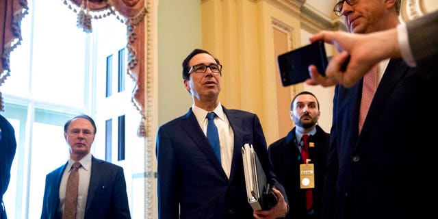 Treasury Secretary Steven Mnuchin, center, accompanied by White House Legislative Affairs Director Eric Ueland, right, stops to speak to reporters as they walk to the offices of Senate Majority Leader Mitch McConnell of Ky. on Capitol Hill in Washington, Monday, March 23, 2020, while the Senate is working to pass a coronavirus relief bill. (AP Photo/Andrew Harnik)