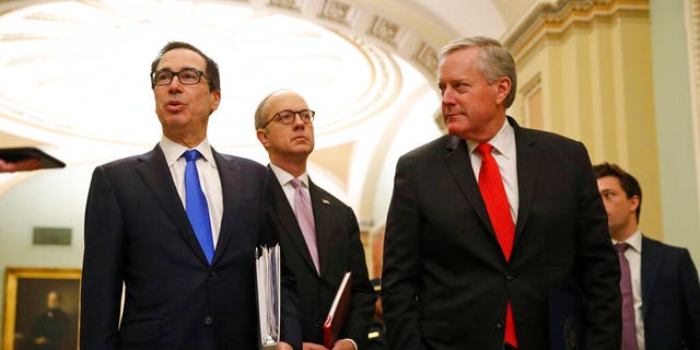 Treasury Secretary Steven Mnuchin, left, accompanied by White House Legislative Affairs Director Eric Ueland and acting White House chief of staff Mark Meadows, speaks with reporters as he walks to the offices of Senate Majority Leader Mitch McConnell of Ky. on Capitol Hill in Washington, Tuesday, March 24, 2020. (AP Photo/Patrick Semansky)