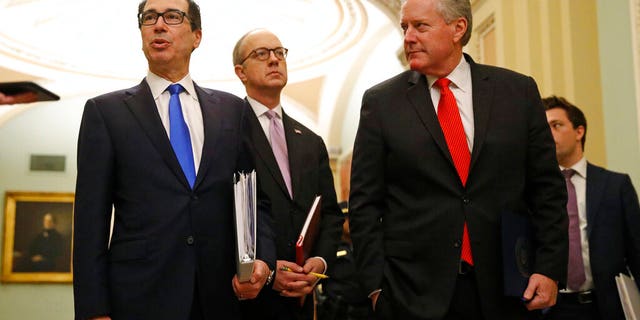 Treasury Secretary Steven Mnuchin, left, accompanied by White House Legislative Affairs Director Eric Ueland and acting White House chief of staff Mark Meadows, speaks with reporters as he walks to the offices of Senate Majority Leader Mitch McConnell of Ky. on Capitol Hill in Washington, Tuesday, March 24, 2020. (AP Photo/Patrick Semansky)