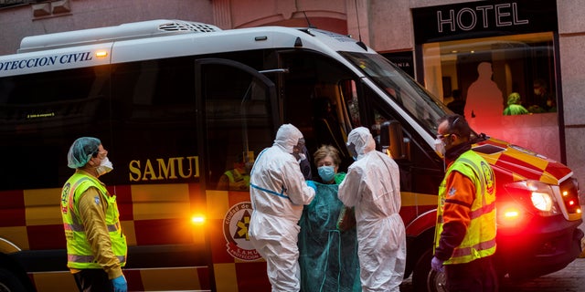 A patient, center, is transferred to a medicalized hotel during the COVID-19 outbreak in Madrid, Spain, Tuesday, March 24, 2020. 