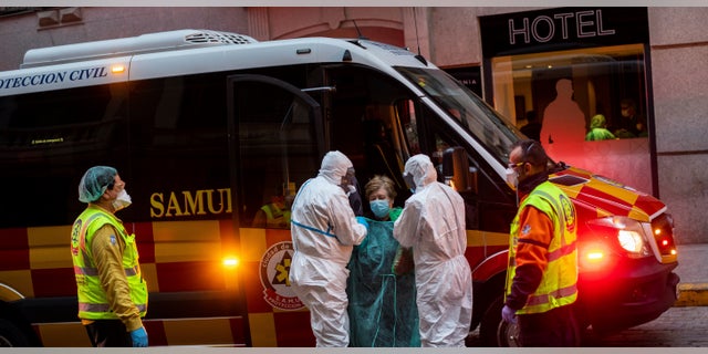 A patient, center, is transferred to a medicalized hotel during the COVID-19 outbreak in Madrid, Spain, Tuesday, March 24, 2020.