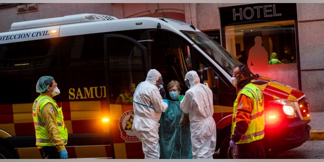 A patient, center, is transferred to a medicalized hotel during the COVID-19 outbreak in Madrid, Spain, Tuesday, March 24, 2020. 