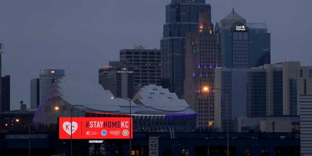 A sign urges residents to stay home as motorists drive past downtown Tuesday, March 24, 2020 on the first day of a stay-at-home order in Kansas City, Mo. Kansas City and surrounding counties instituted a 30-day mandatory stay-at-home order in an effort to stem the spread of the coronavirus. (AP Photo/Charlie Riedel)