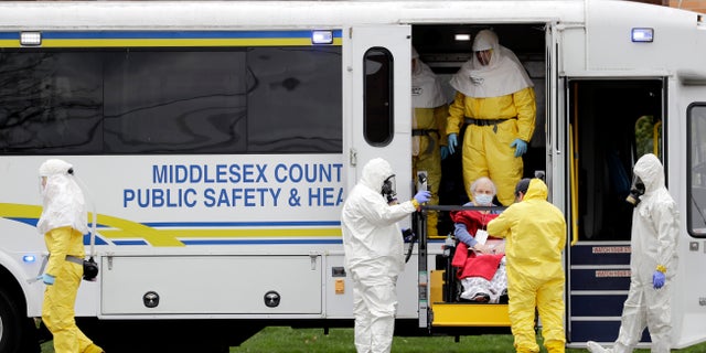 Residents from St. Joseph's Senior Home are helped onto buses in Woodbridge, N.J., Wednesday, March 25, 2020. More than 90 residents of the nursing home are being transferred to a facility in Whippany after 24 tested positive for COVID-19, according to a spokeswoman for CareOne.