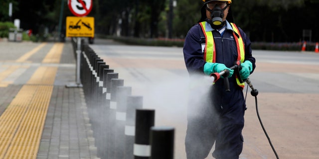 A worker sprays disinfectant at the pedestrian walkway at Senayan Sports Complex amid coronavirus outbreak, in Jakarta, Indonesia, Thursday, March 26, 2020. The new coronavirus causes mild or moderate symptoms for most people, but for some, especially older adults and people with existing health problems, it can cause more severe illness or death. (AP Photo/Dita Alangkara)