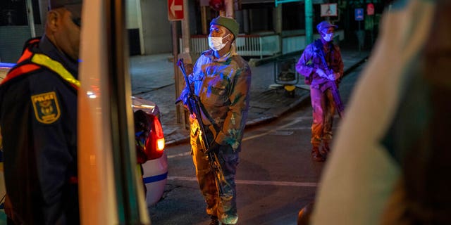 South African Defense Forces and police check a minibus driver who violated the lockdown downtown Johannesburg, South Africa, Friday, March 27, 2020. 