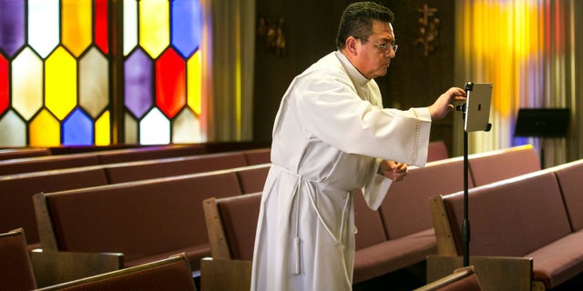 The Rev. César Vega sets up a tablet to livestream Mass to home-bound congregants Friday, March 27, 2020, at Holy Family Catholic Church in Yakima, Wash.