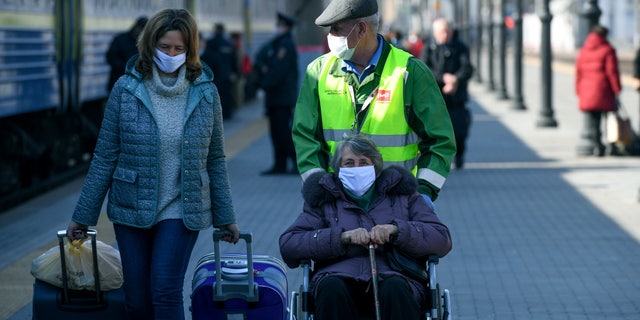 Russian citizens, some of them wearing face masks, on a platform after arriving by a special train from Ukraine in Moscow on Saturday. (AP Photo)