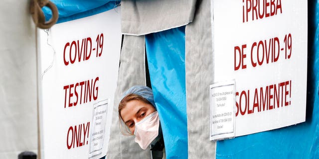 A medical worker sticks her head outside a COVID-19 testing tent set up outside Elmhurst Hospital Center in New York, Saturday, March 28, 2020. The hospital is caring for a high number of coronavirus patients in the city, and New York leads the nation in the number of cases, according to Johns Hopkins University, which is keeping a running tally. (AP Photo/Kathy Willens)