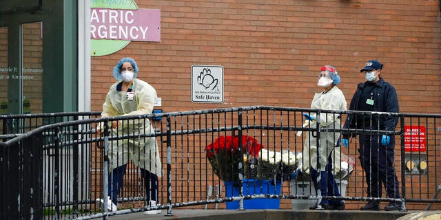 Emergency room nurses gather flowers donated to the hospital staff on a ramp outside Elmhurst Hospital Center's ER after a neighbor dropped them off, Saturday, March 28, 2020. The Queens borough hospital has been heavily taxed treating coronavirus patients in recent weeks. New York leads the nation in the number of cases, according to Johns Hopkins University, which is keeping a running tally. (AP Photo/Kathy Willens)