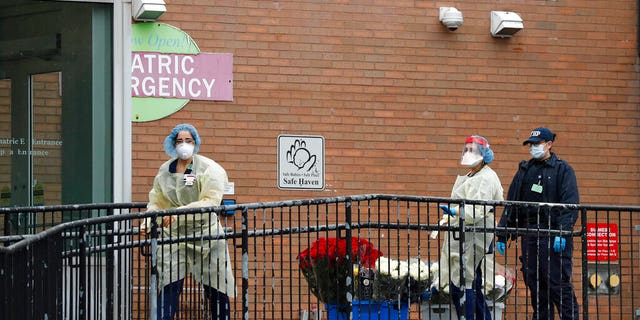 Emergency room nurses gather flowers donated to the hospital staff on a ramp outside Elmhurst Hospital Center's ER after a neighbor dropped them off, Saturday, March 28, 2020. The Queens borough hospital has been heavily taxed treating coronavirus patients in recent weeks. New York leads the nation in the number of cases, according to Johns Hopkins University, which is keeping a running tally. (AP Photo/Kathy Willens)