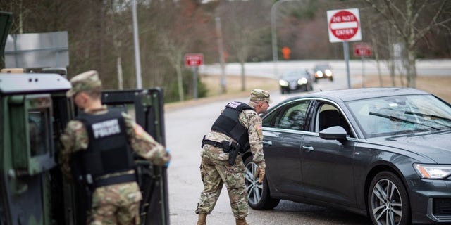 A member of the Rhode Island National Guard Military Police directs a motorist with New York license plates at a checkpoint on Interstate 95 in Hope Valley, R.I., March 28, 2020, (Associated Press)