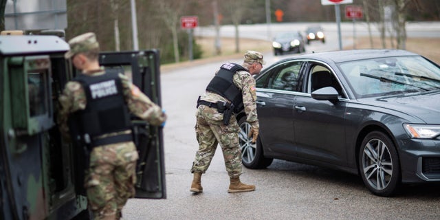 A member of the Rhode Island National Guard Military Police directs a motorist with New York license plates at a checkpoint on Interstate 95 in Hope Valley, R.I., March 28, 2020, (Associated Press)