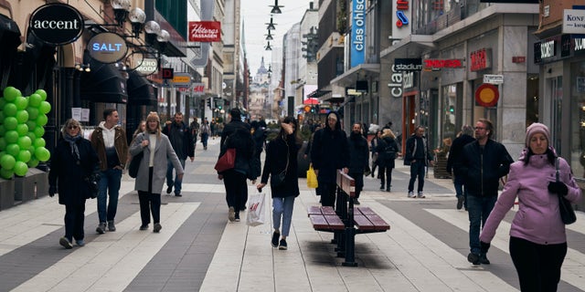 FILE - People walk along the main pedestrian shopping street in Stockholm, Sweden, Wednesday, March 25, 2020. The streets of Stockholm are quiet but not deserted. After a long, dark Scandinavian winter, the coronavirus pandemic is not keeping Swedes at home even while citizens in many parts of the world are sheltering in place and won't find shops or restaurants open on the few occasions they are permitted to venture out. (AP Photo/David Keyton, File)