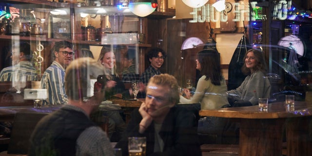 FILE - People sit in a bar in Stockholm, Sweden, Wednesday, March 25, 2020. The streets of Stockholm are quiet but not deserted. People still sit at outdoor cafes in the center of Sweden's capital. Vendors still sell flowers. Teenagers still chat in groups in parks. Some still greet each other with hugs and handshakes. After a long, dark Scandinavian winter, the coronavirus pandemic is not keeping Swedes at home even while citizens in many parts of the world are sheltering in place and won't find shops or restaurants open on the few occasions they are permitted to venture out. (AP Photo/David Keyton, File)
