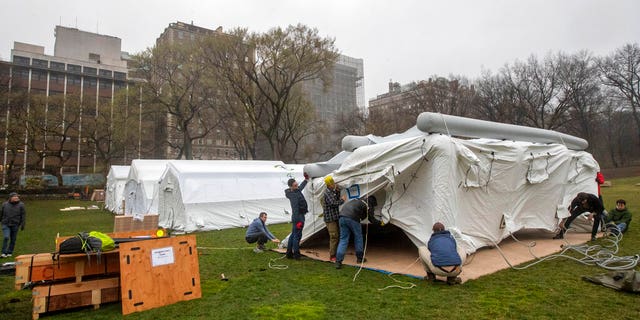 A Samaritan's Purse crew works on building an emergency field hospital equipped with a respiratory unit in New York's Central Park across from the Mount Sinai Hospital, Sunday, March 29, 2020. (AP Photo/Mary Altaffer)