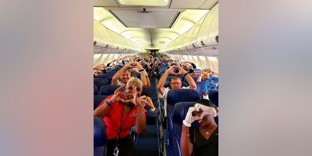 Health care workers, other passengers and flight crew aboard a Southwest flight from Atlanta to New York's LaGuardia Airport holding their hands in the shape of a heart before takeoff in Atlanta. (Dayartra Etheridge via AP)