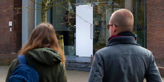 Two people look at the glass door which was smashed during a break-in at the Singer Museum in Laren, Netherlands. (AP Photo/Peter Dejong)
