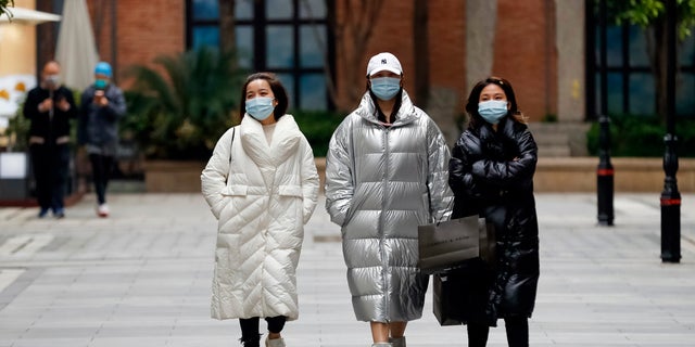 In this photo released by Xinhua News Agency, women wearing protective masks to prevent the new coronavirus outbreak walk on a re-opened commercial street in Wuhan in central China's Hubei province on Monday. (Shen Bohan/Xinhua via AP)
