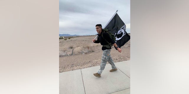 Airman David Saenz, 21, holds a Prinsoers of War flag while walking the streets of Las Cruces, N.M on Sunday.