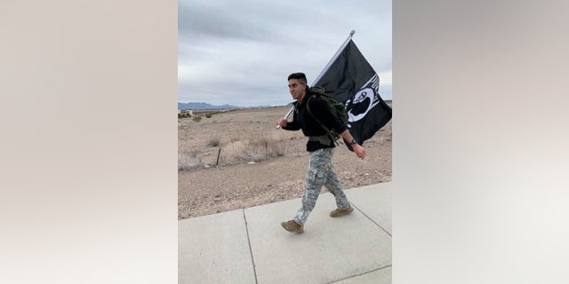 Airman David Saenz, 21, holds a Prinsoers of War flag while walking the streets of Las Cruces, N.M on Sunday.