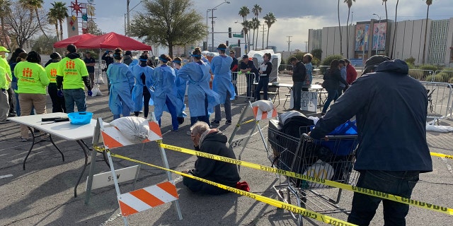 People wait to be screened before entering an homeless shelter set up in a parking lot in Las Vegas on Saturday.