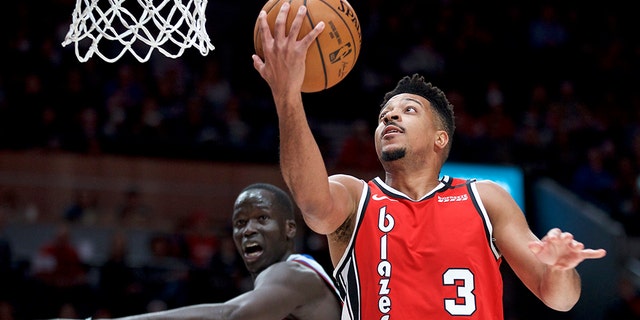 Portland Trail Blazers guard CJ McCollum, right, shoots over Detroit Pistons forward Thon Maker during the first half of an NBA basketball game in Portland, Ore., Sunday, Feb. 23, 2020. (AP Photo/Craig Mitchelldyer)