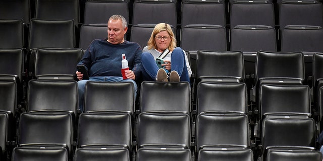 Basketball fans sit in an empty section after it is announced that an NBA basketball game between the Oklahoma City Thunder and Utah Jazz in Oklahoma City has been postponed, Wednesday, March 11, 2020. (AP Photo/Kyle Phillips)