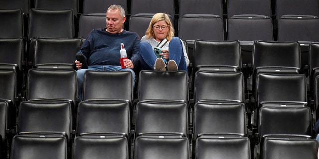 Basketball fans sit in an empty section after it is announced that an NBA basketball game between the Oklahoma City Thunder and Utah Jazz in Oklahoma City has been postponed, Wednesday, March 11, 2020. (AP Photo/Kyle Phillips)