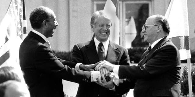 Egyptian President Anwar Sadat, left, U.S. President Jimmy Carter, center, and Israeli Prime Minister Menachem Begin clasp hands on the north lawn of the White House after signing the peace treaty between Egypt and Israel on March 26, 1979. (AP Photo/ Bob Daugherty)