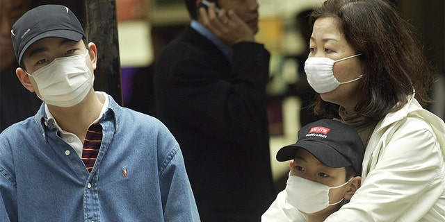 Flashback: A family wear masks on a street in the Central business district of Hong Kong as an outbreak of SARS grips the territory in March 2003.