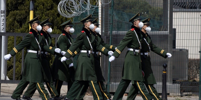 Chinese paramilitary wearing masks march by during their duty in an embassy district in Beijing on Monday, March 16, 2020.