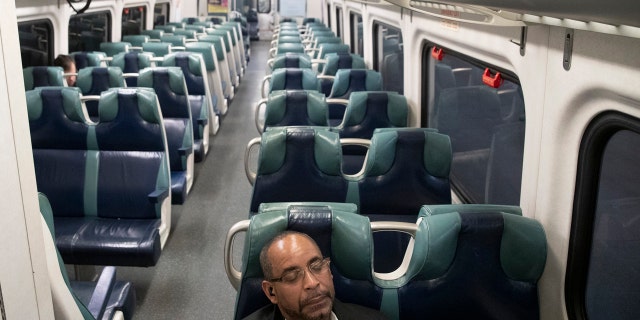 A commuter sits in an otherwise empty car as he waits for the 7:58 p.m. train to Hudson to leave Grand Central Terminal, Tuesday, March 17, 2020, in New York.
