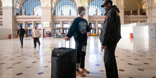 A traveler talks with a security officer at Washington Union Station, a major transportation hub in the nation's capital, Monday, March 16, 2020.