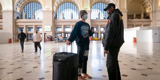 A maior parte dos trabalhadores não se sente segura com a reabertura dos comércios nos Estados Unidos 1 A traveler talks with a security officer at Washington Union Station, a major transportation hub in the nation's capital, Monday, March 16, 2020.