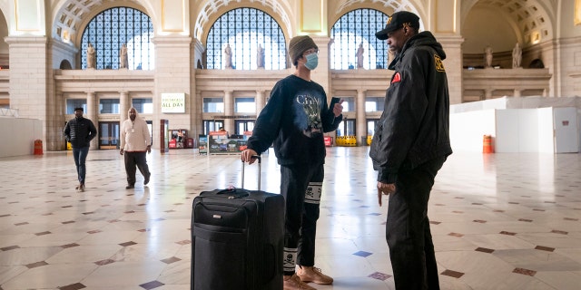 A traveler talks with a security officer at Washington Union Station, a major transportation hub in the nation's capital, Monday, March 16, 2020.