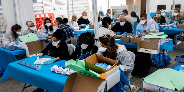 Electoral officials count ballots cast by Israelis under home quarantine after returning from Coronavirus infected zones in the city of Shoham, Israel, Wednesday. (AP Photo/Tsafrir Abayov)