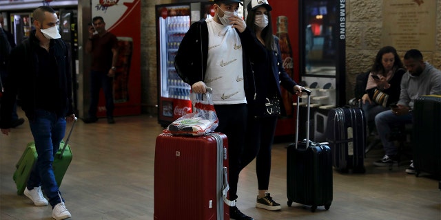 Passengers wearing protective masks arrive in Ben Gurion Airport near Tel Aviv, Israel, Thursday, Feb. 27, 2020. (AP Photo/Ariel Schalit)
