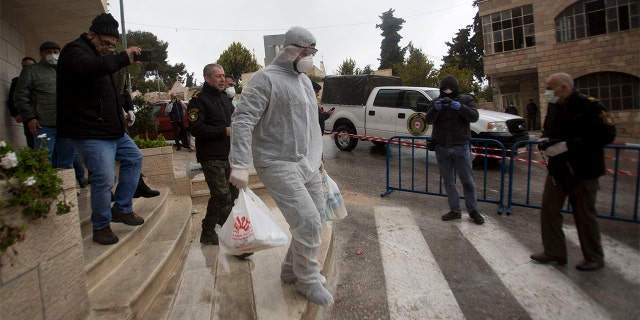 Palestinian policeman delivers supplies to the hotel staff which tested positive to coronavirus to a hotel in Bethlehem, West Bank, Friday. (AP Photo/Majdi Mohammed)