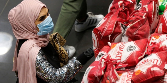 A woman wears a mask and gloves, as she checks products at a supermarket as people begin to stock up on provisions, in Beirut, Lebanon, Wednesday. (AP Photo/Hussein Malla)