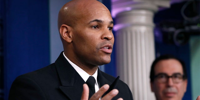 U.S. Surgeon General Jerome Adams speaks during a briefing on coronavirus in the Brady press briefing room at the White House, Saturday, March 14, 2020, in Washington, as Treasury Secretary Steven Mnuchin listens. Adams has said in no uncertain terms that any coronavirus vaccine distributed to Americans will be safe and effective. (AP Photo/Alex Brandon)