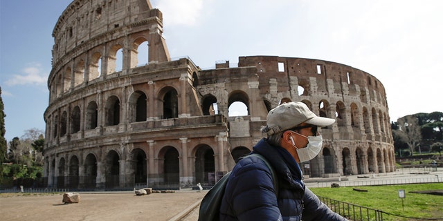 A man with a mask riding past the Colosseum in Rome on Sunday. (AP Photo/Alessandra Tarantino)