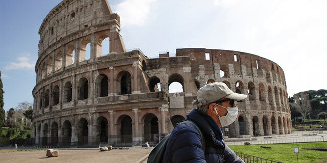 A man with a mask riding past the Colosseum in Rome on Sunday. (AP Photo/Alessandra Tarantino) A man with a mask riding past the Colosseum in Rome on Sunday. (AP Photo/Alessandra Tarantino)
