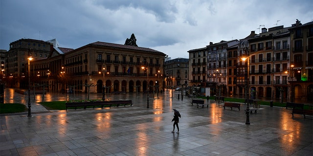 A lone person walking through an empty Plaza del Castillo square in the old city, in Pamplona, northern Spain, on Sunday. (AP Photo/Alvaro Barrientos)